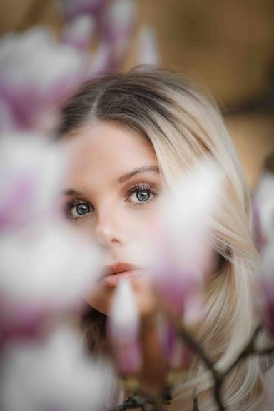 Porträt einer Frau mit blonden Haaren, umgeben von Magnolienblüten.